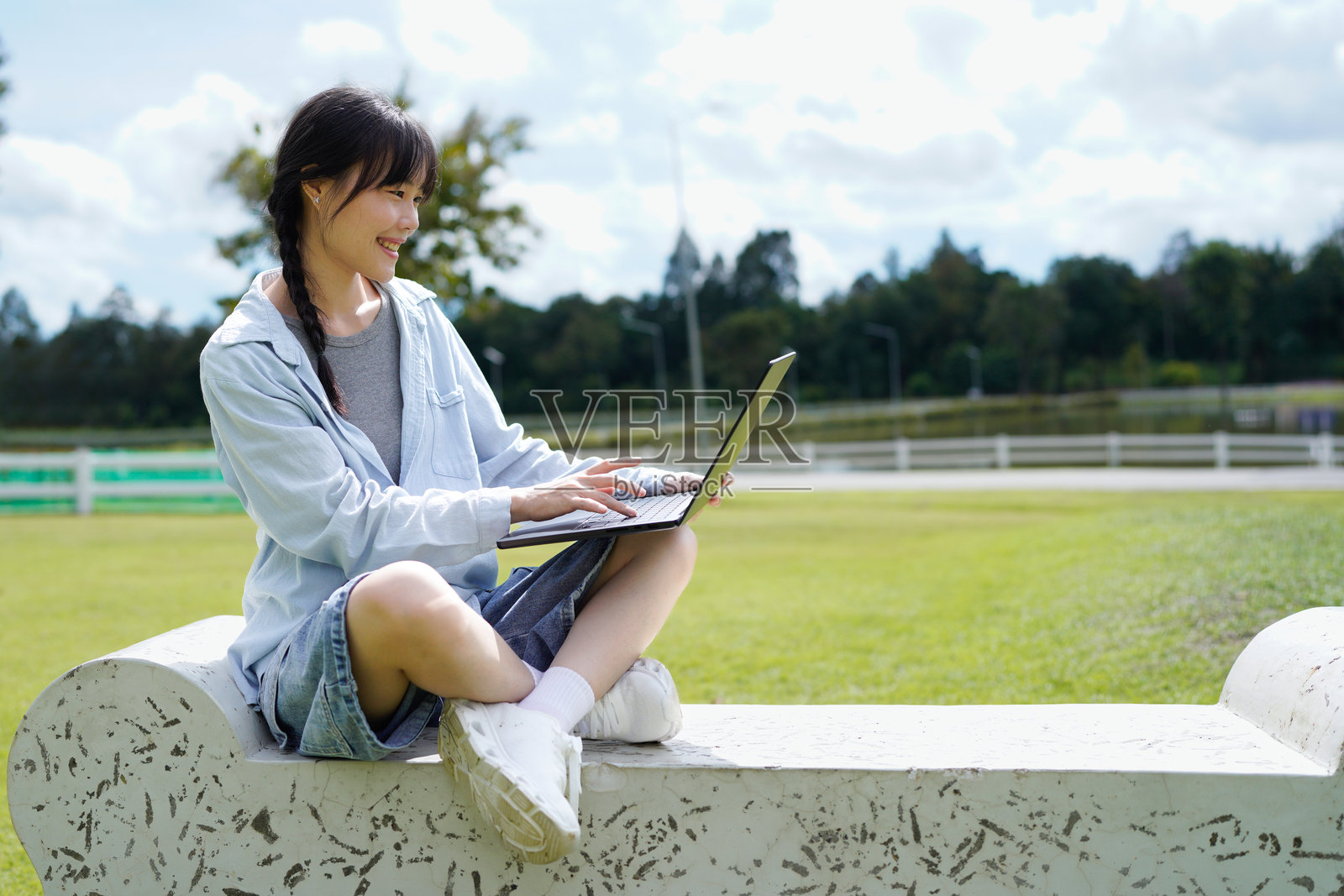 一位快乐年轻美丽的混血学生女孩，在户外自然公园里使用笔记本电脑。照片摄影图片
