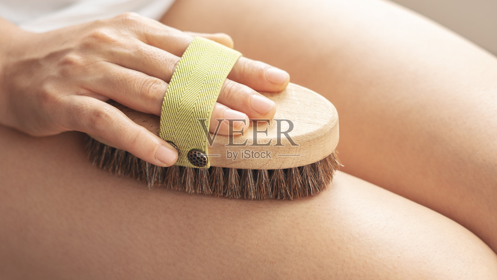 女子在室内使用按摩刷进行抗橘皮组织按摩，特写照片摄影图片