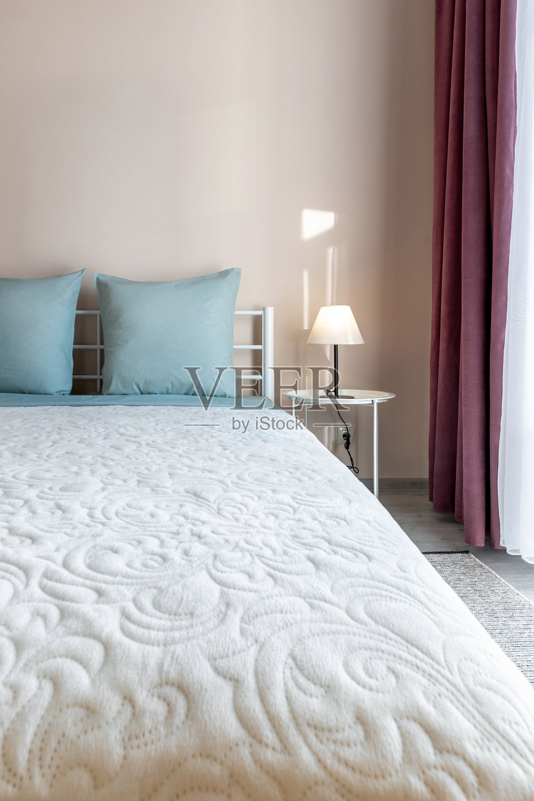 极简卧室，配有蓝色抱枕和柔软的白色床罩照片摄影图片