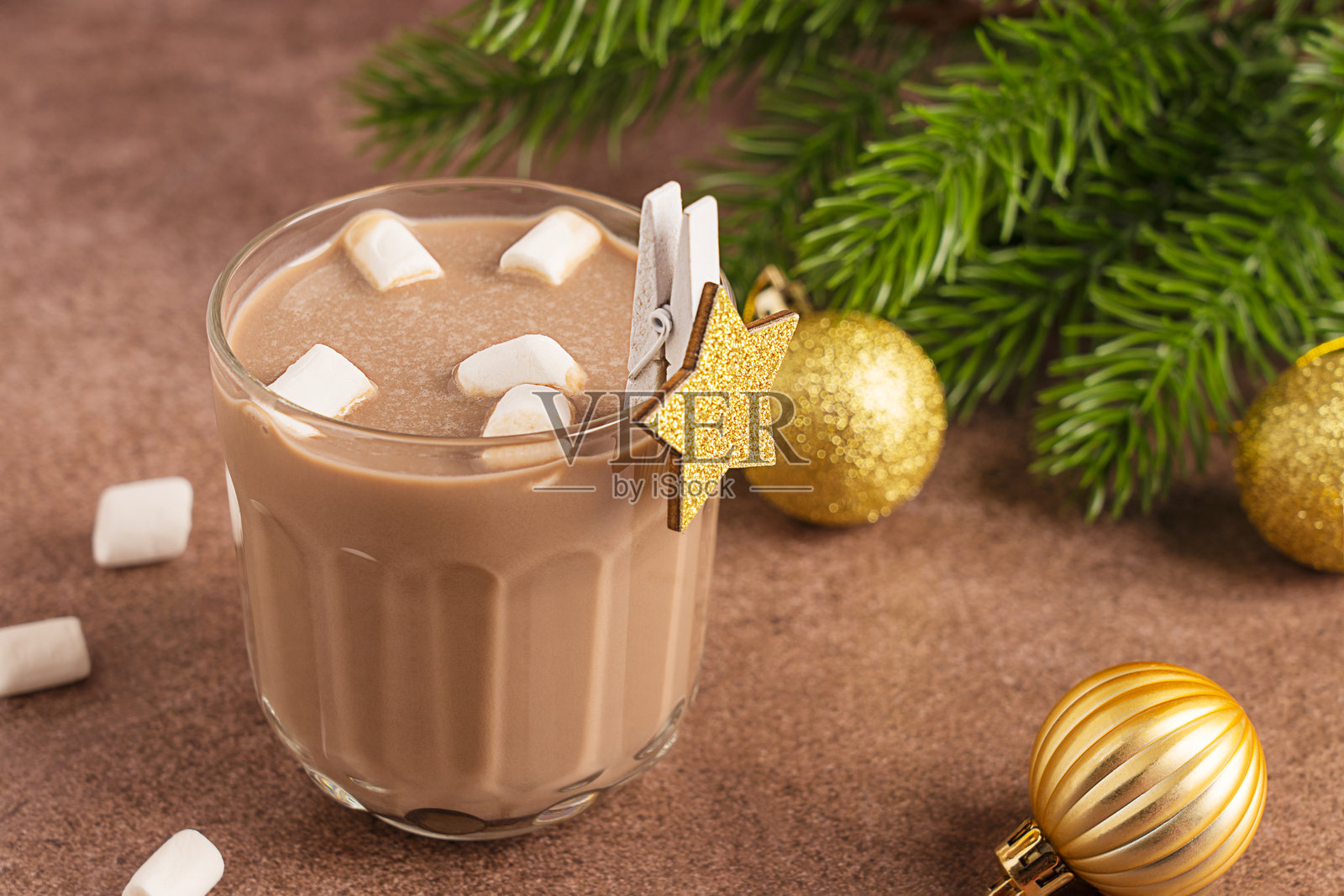 节日热巧克力或可可的玻璃杯，配有棉花糖和金色圣诞装饰照片摄影图片