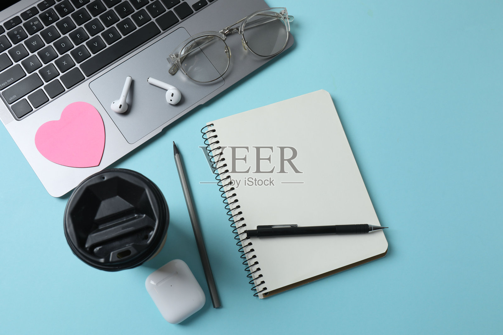 蓝底上的笔记本电脑、眼镜、咖啡、耳机和记事本，并留有文本空间照片摄影图片