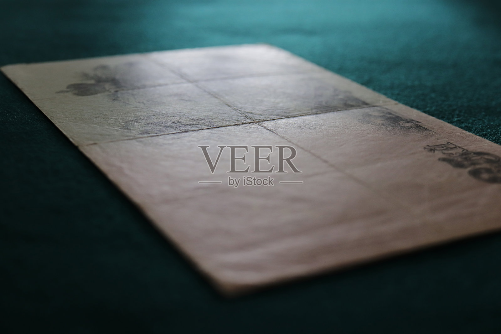 一张带有模糊设计的复古纸张，铺在有纹理的绿色表面上照片摄影图片