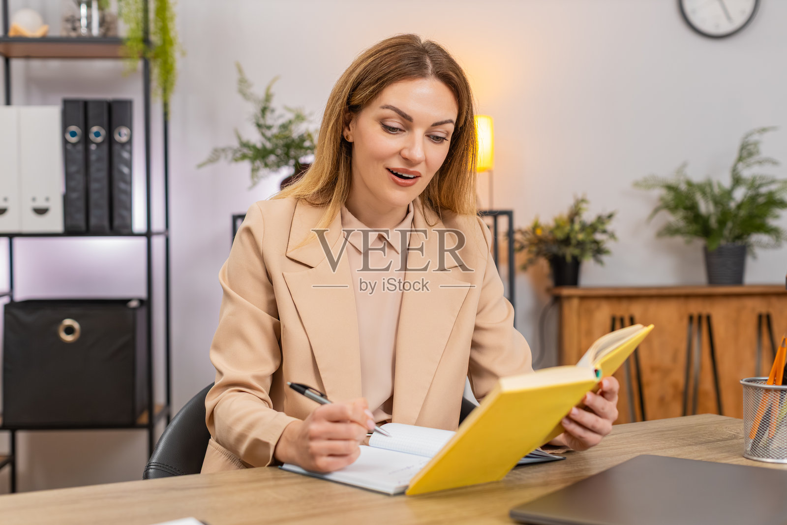 女商人阅读领导力书籍，对引言微笑，并在笔记本上写下促进成长和愿景的想法照片摄影图片