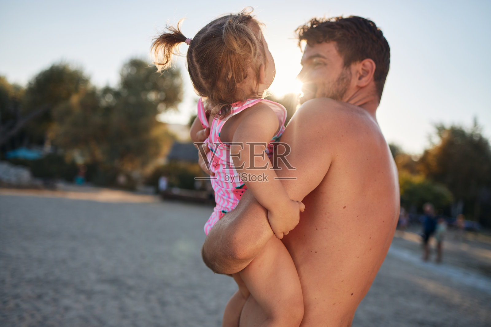 父亲在日落时分于海滩上抱着女儿拥抱照片摄影图片