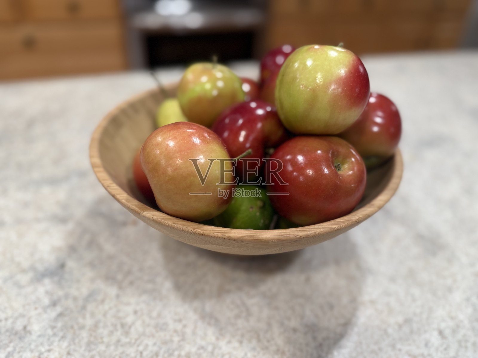 木碗里摆放着成熟的苹果，碗放在桌子上照片摄影图片