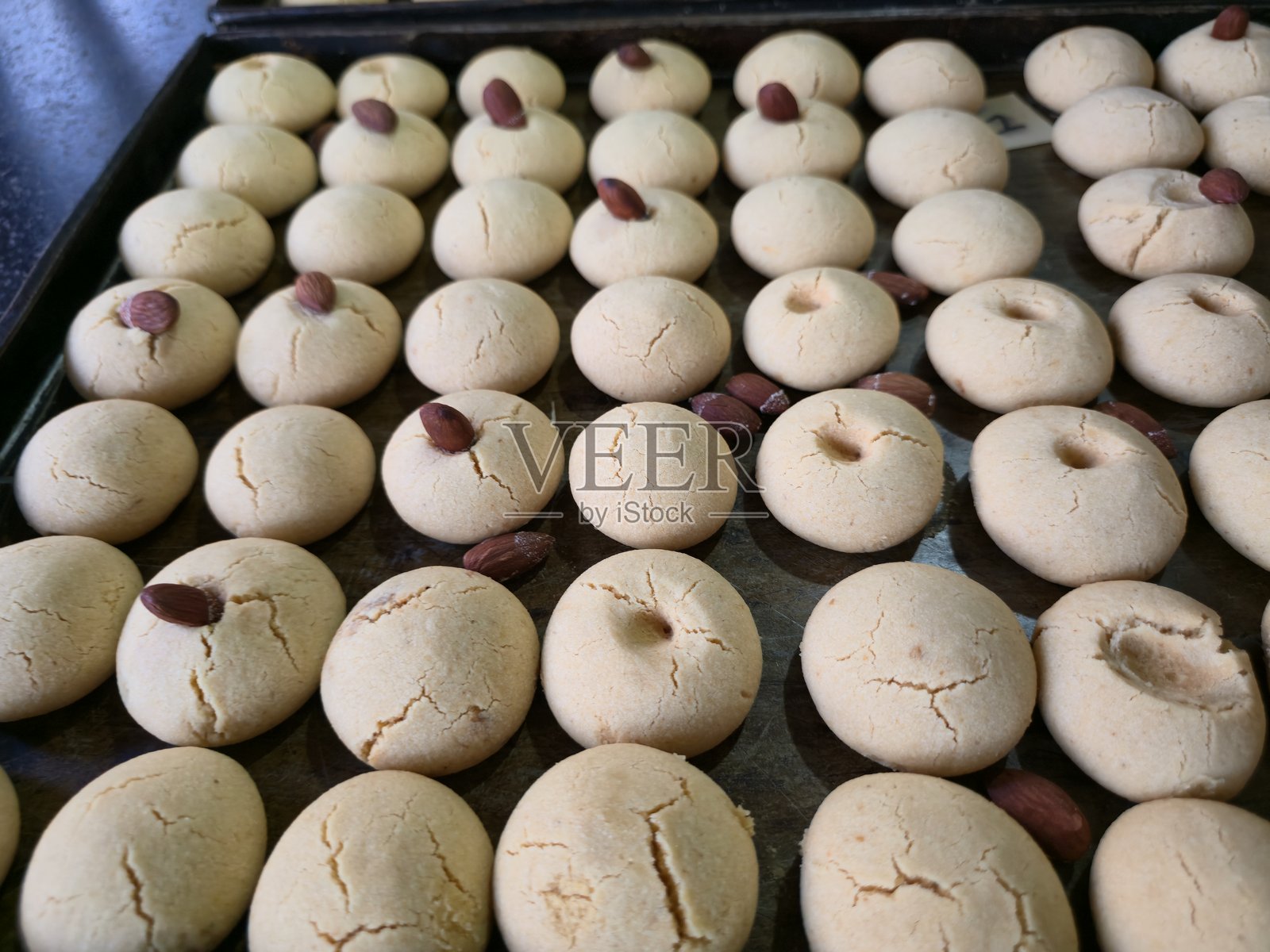 烤箱托盘上摆放着刚出炉的、撒有杏仁的南坎泰饼干照片摄影图片