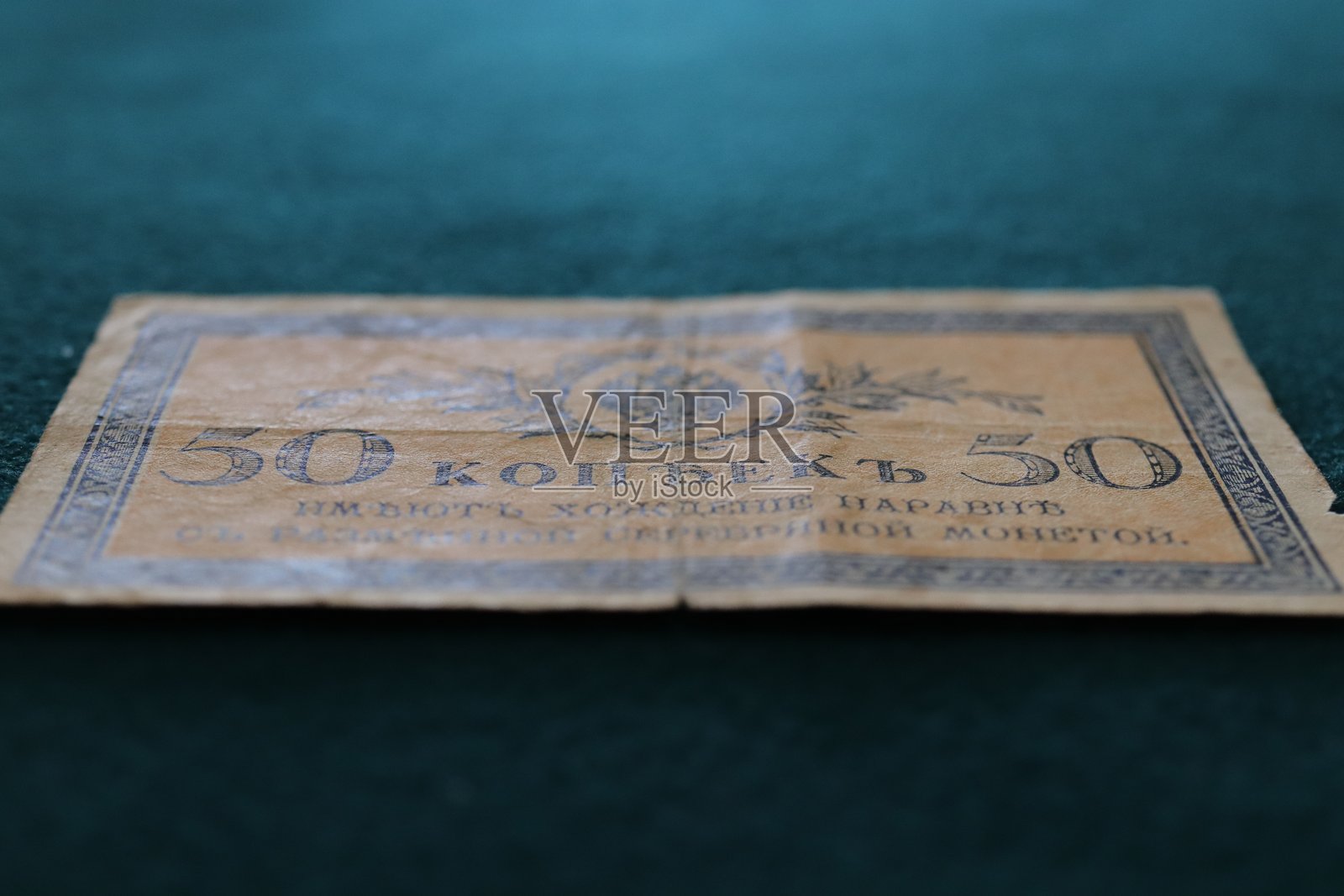 一张带有复杂图案和褪色色彩的旧50戈比纸币，放置在绿色表面上照片摄影图片