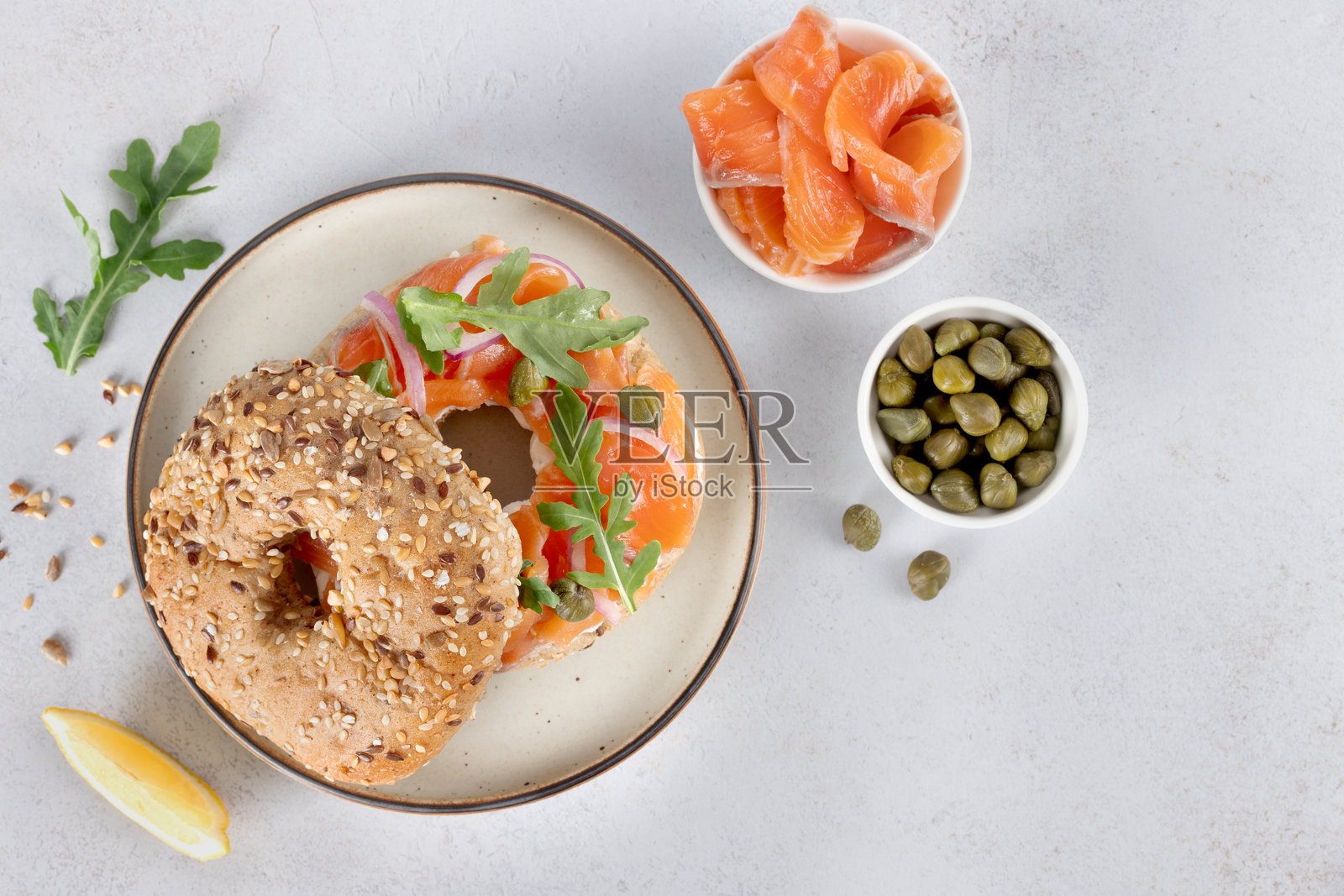 白底烟熏三文鱼、奶油芝士、黄瓜和芝麻菜贝果。俯视视角。照片摄影图片