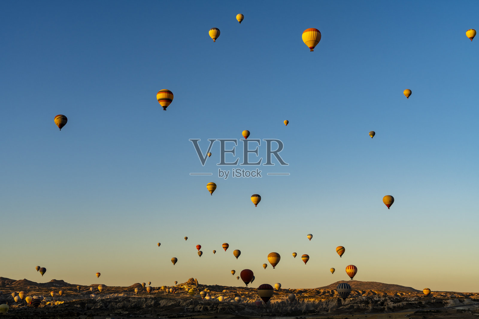 土耳其卡帕多奇亚地区，大批热气球正从独特的山地地貌上空升起照片摄影图片