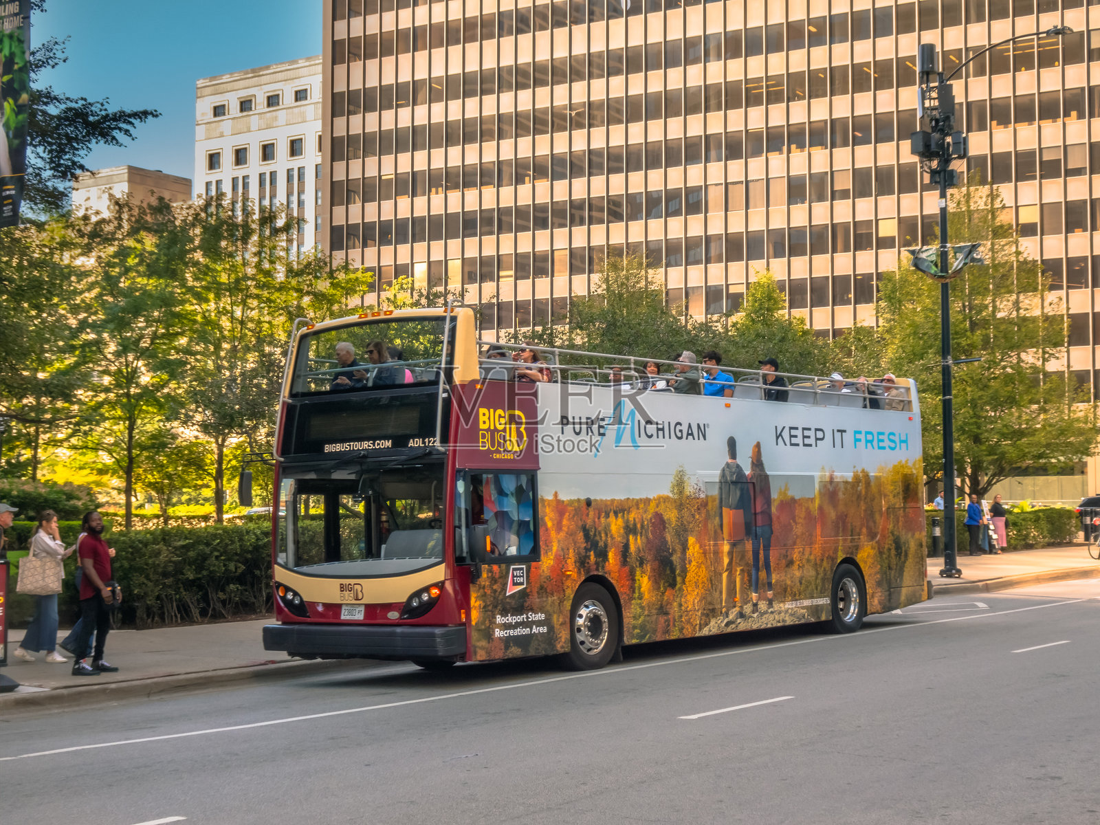 一辆印有“Pure Michigan”品牌标识的“Big Bus Tours”双层巴士,载着游客穿梭于充满活力的城市景象中,展现了都市探索与旅行的魅力。照片摄影图片