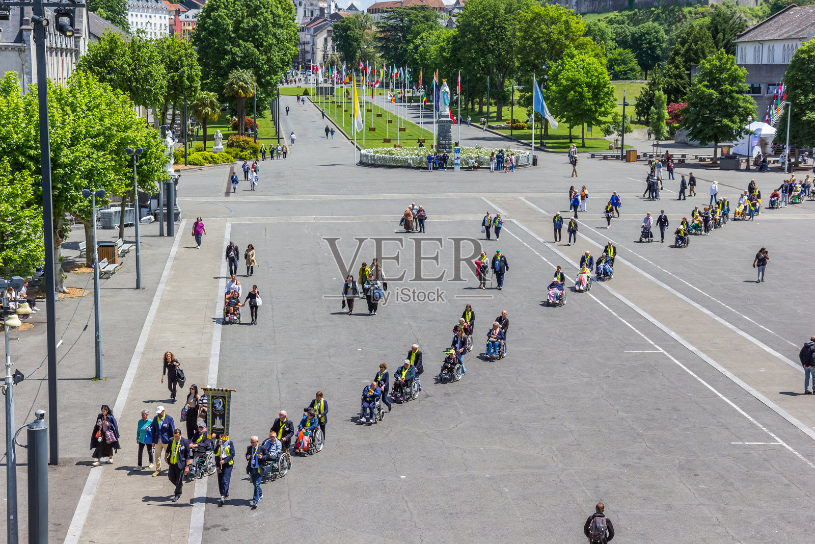 坐着轮椅的老年人在卢尔德圣地广场上穿行照片摄影图片