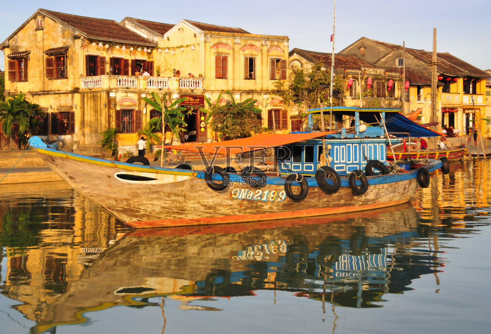 越南会安古镇的粉彩外墙和秋盆河上的渔船照片摄影图片