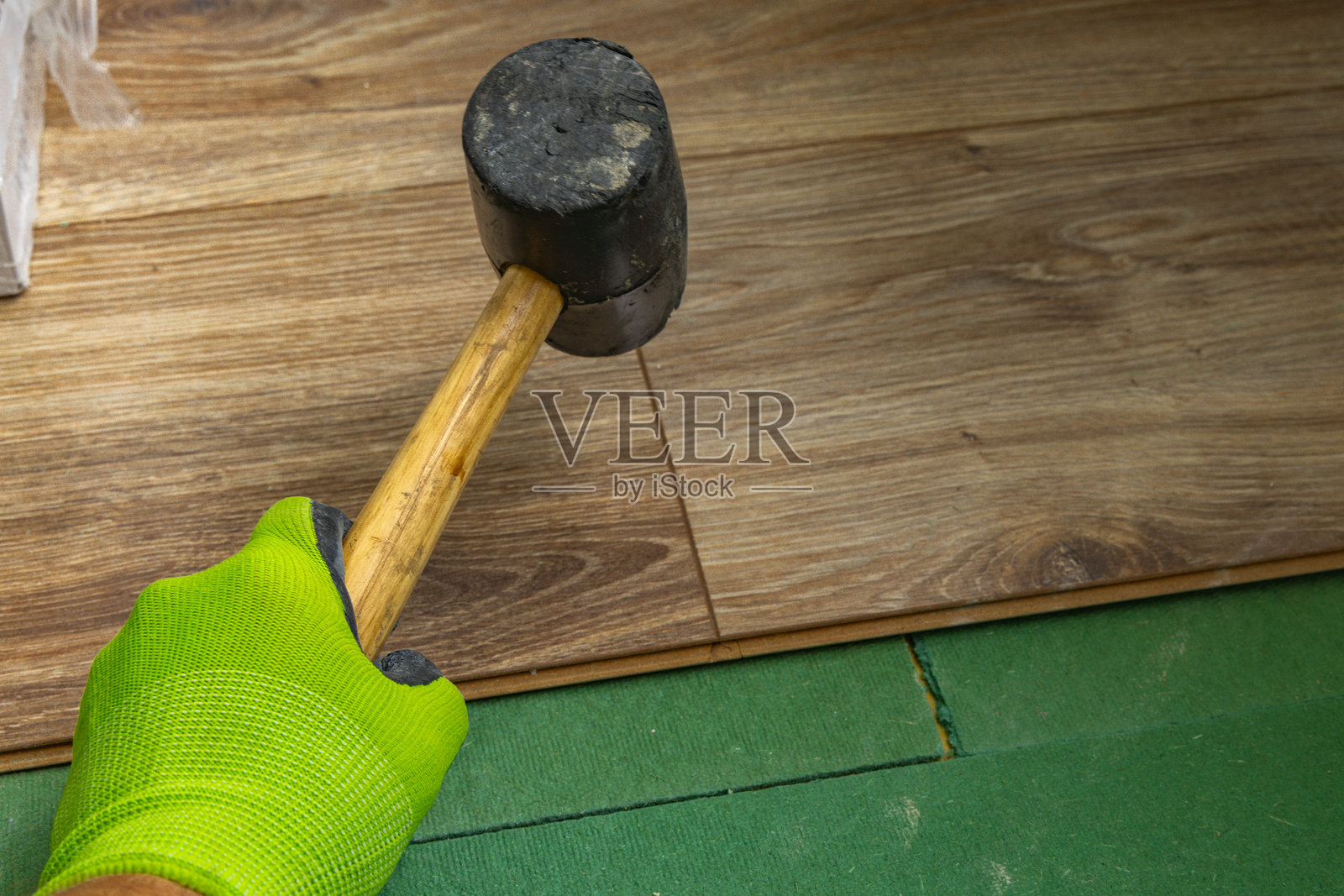 使用橡胶锤安装木地板面板的家居装修工程照片摄影图片