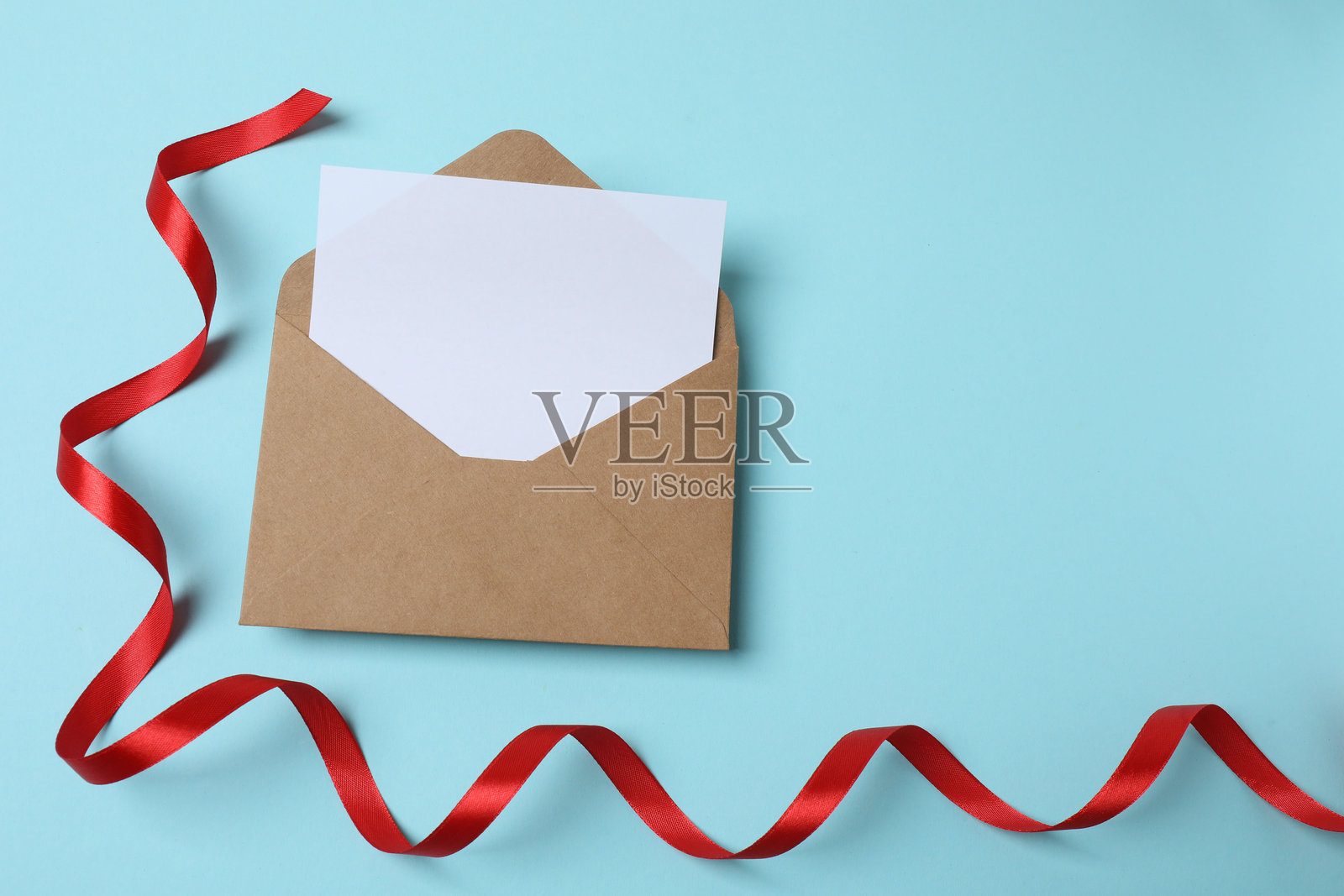 俯视角度拍摄的 वैलेंट丁节装饰品照片，包含粉色蝴蝶结的信封、卷曲的丝带以及打开的粉色信封和一张纸，背景为孤立的粉彩色调的粉色，留有空白空间。照片摄影图片