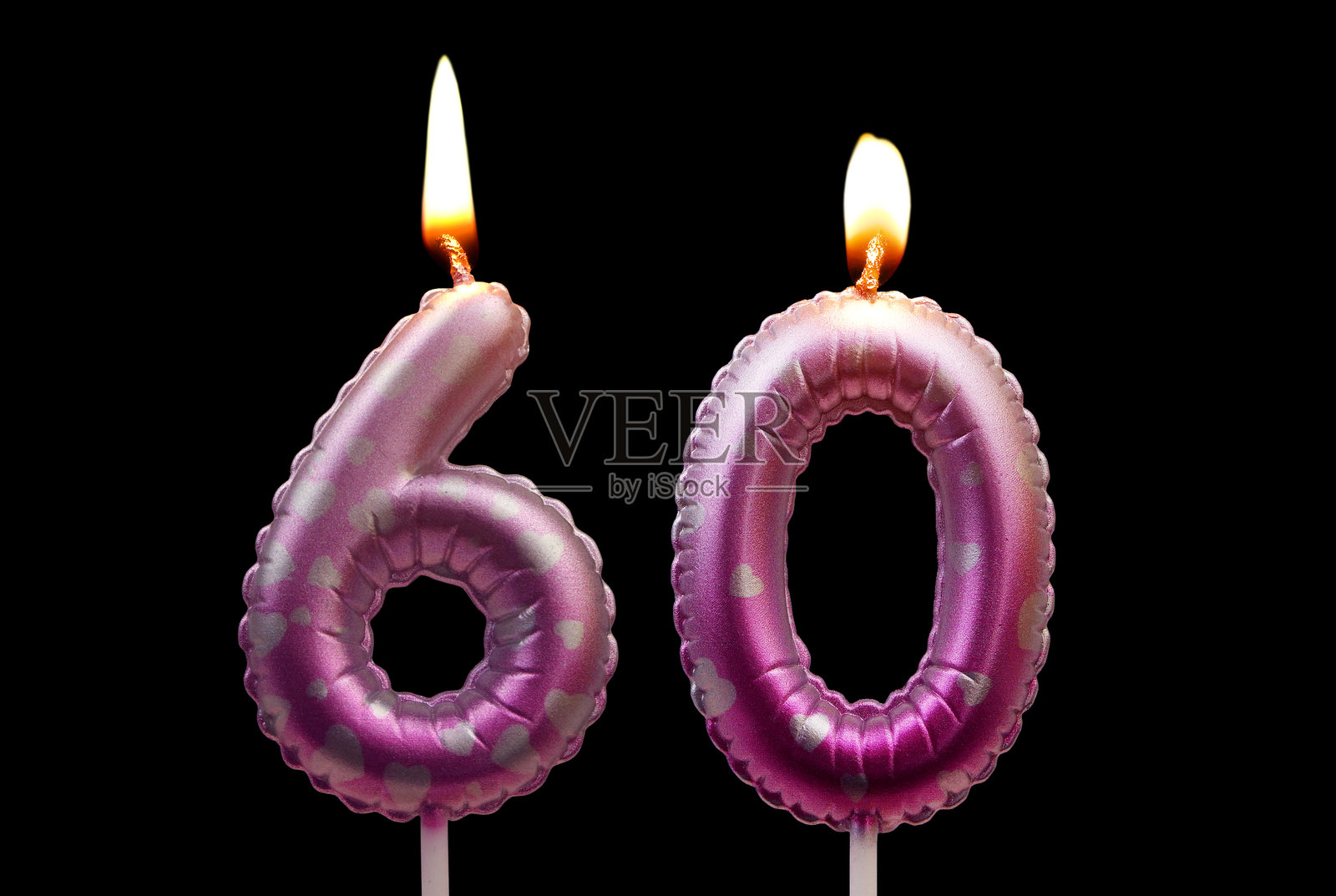 燃烧的粉色生日蜡烛，带有心形图案，孤立在黑色背景上，数字 60照片摄影图片