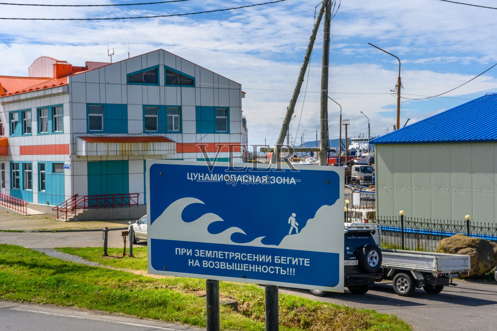 阳光明媚的海港,警示标志提醒居民注意沿海地区海啸危险照片摄影图片