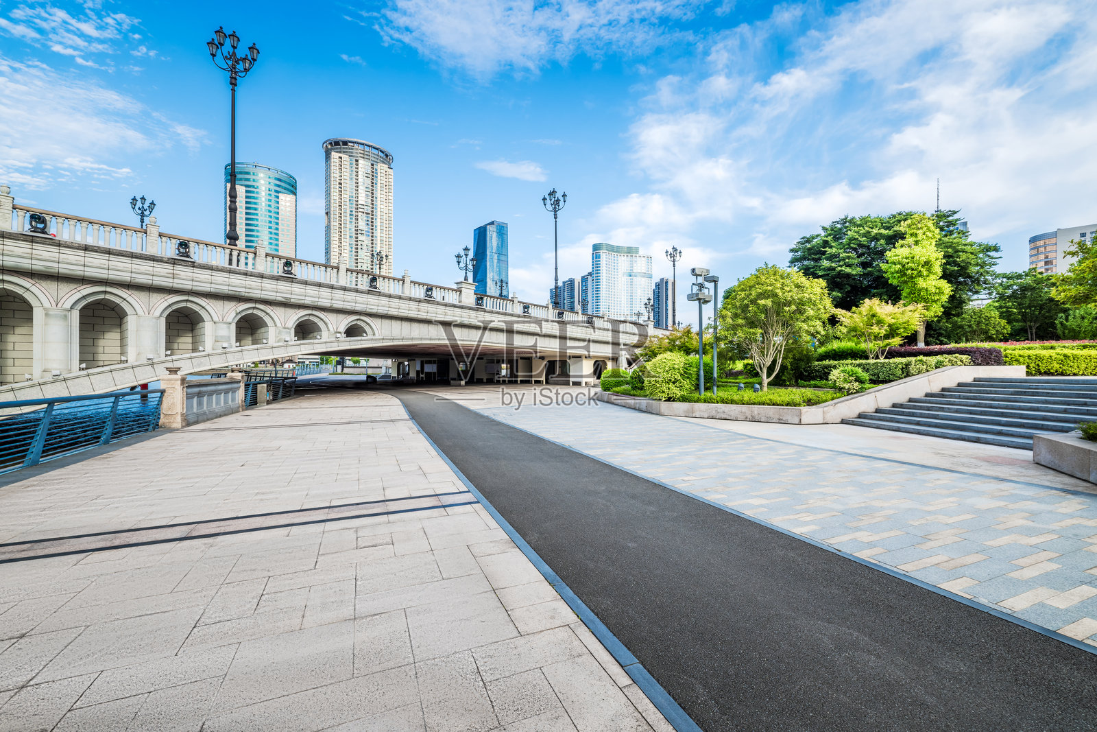 中国宁波，一座现代城市公园，有桥梁和城市天际线，空旷的走道和沥青小径穿过其中。照片摄影图片