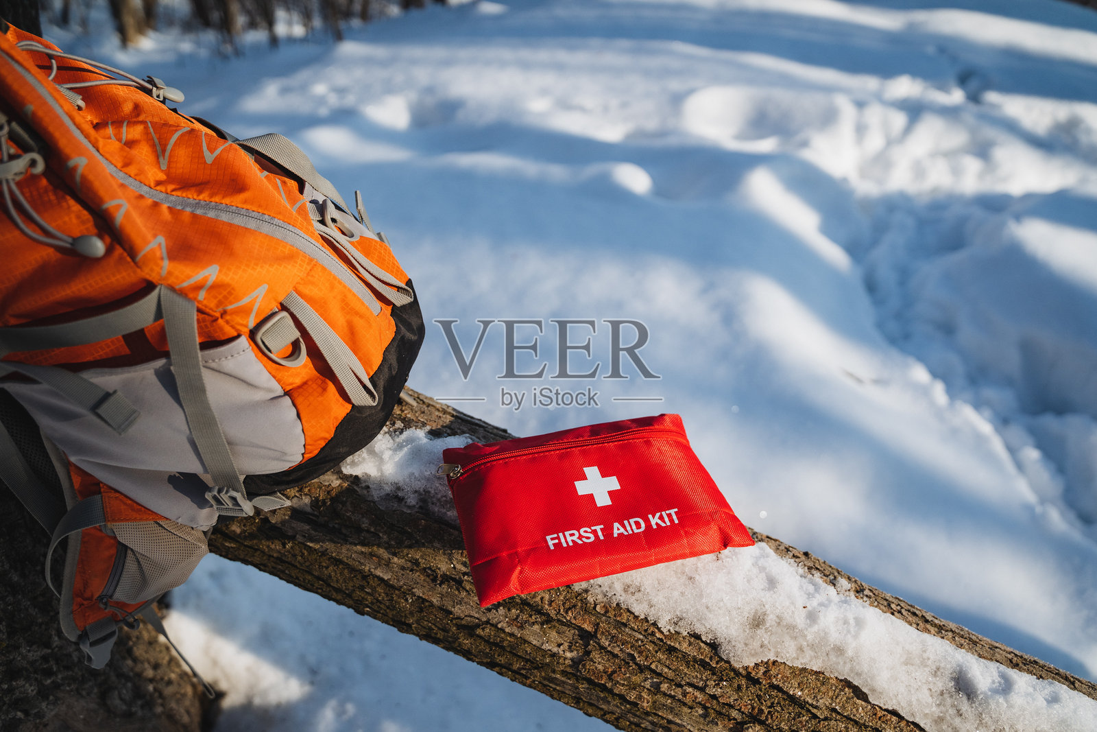 急救箱被醒目地放置在雪地中间的原木上，凸显了其在冬季户外活动或探险中应对紧急情况的重要性照片摄影图片