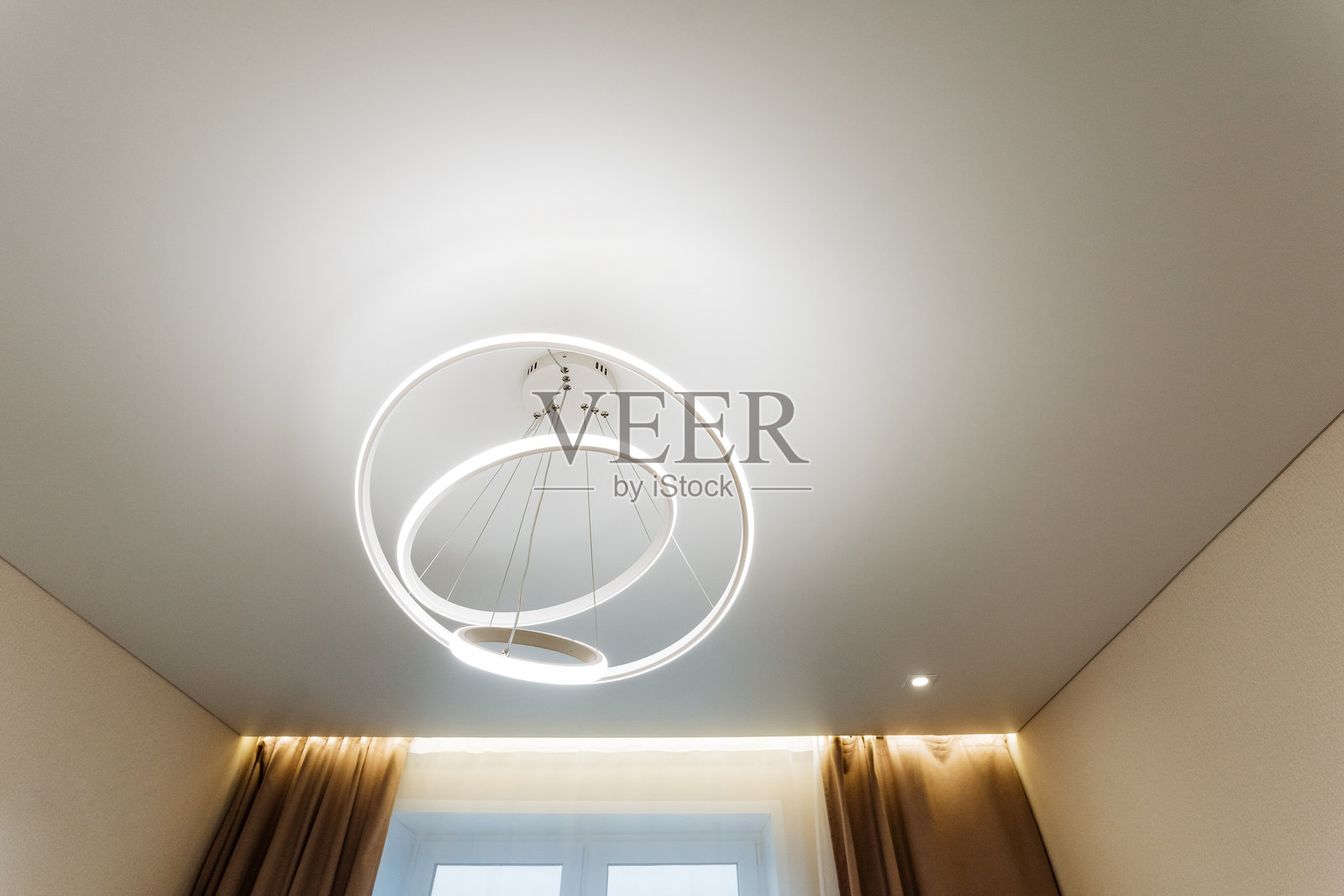 卧室拥有一个洁白的吊顶，上面优雅地悬挂着一盏别致的吊灯，为整个房间的装饰增添了一抹精致感。照片摄影图片