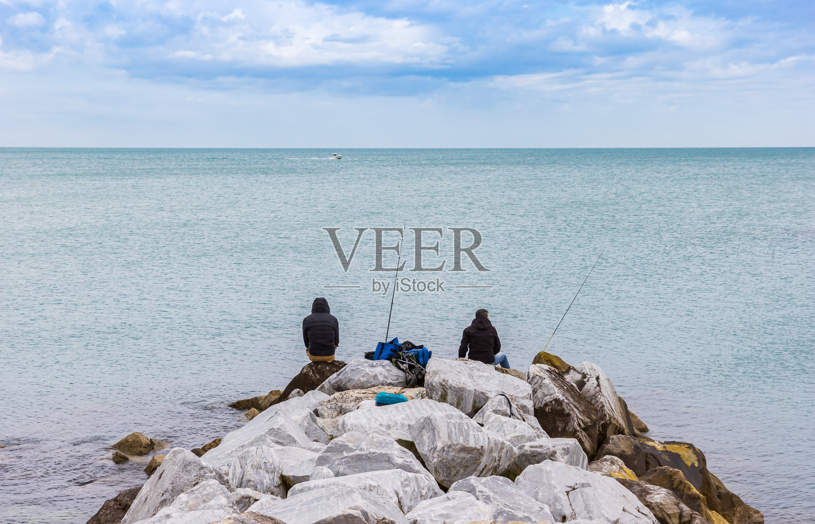 两位男士在比萨码头(Marina di Pisa)的岩石上钓鱼照片摄影图片