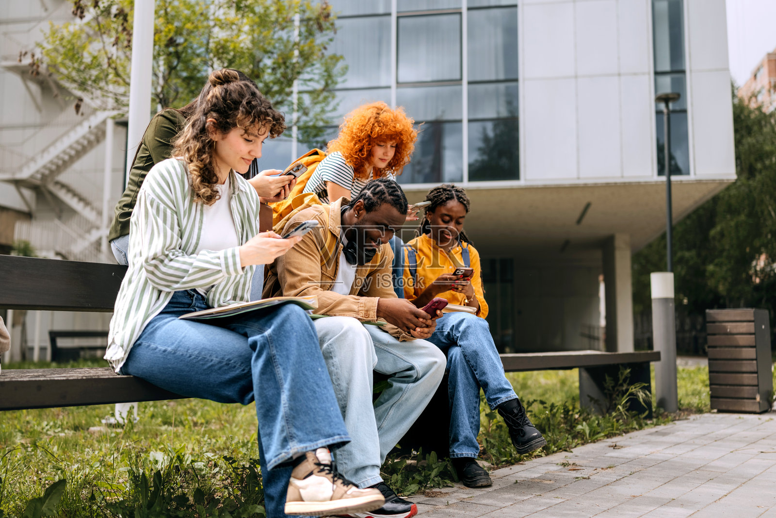 一群大学生在户外使用智能手机照片摄影图片