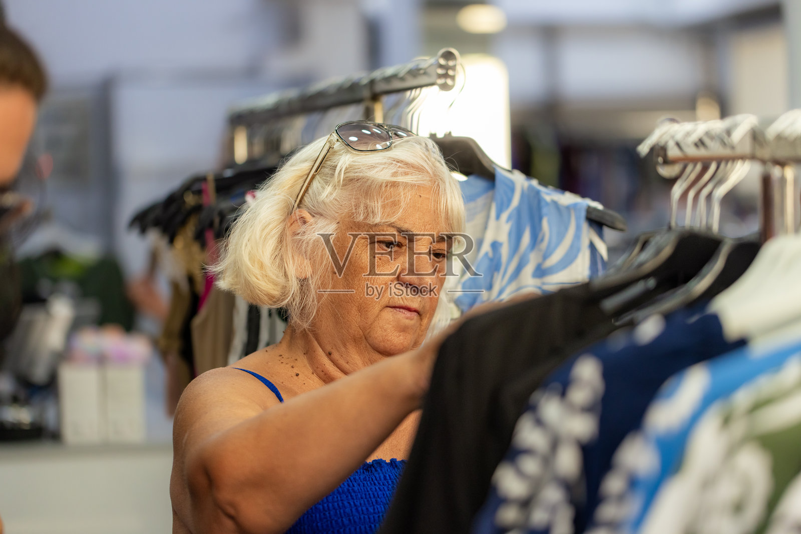 一位成熟的女性在精品店里挑选衣服照片摄影图片