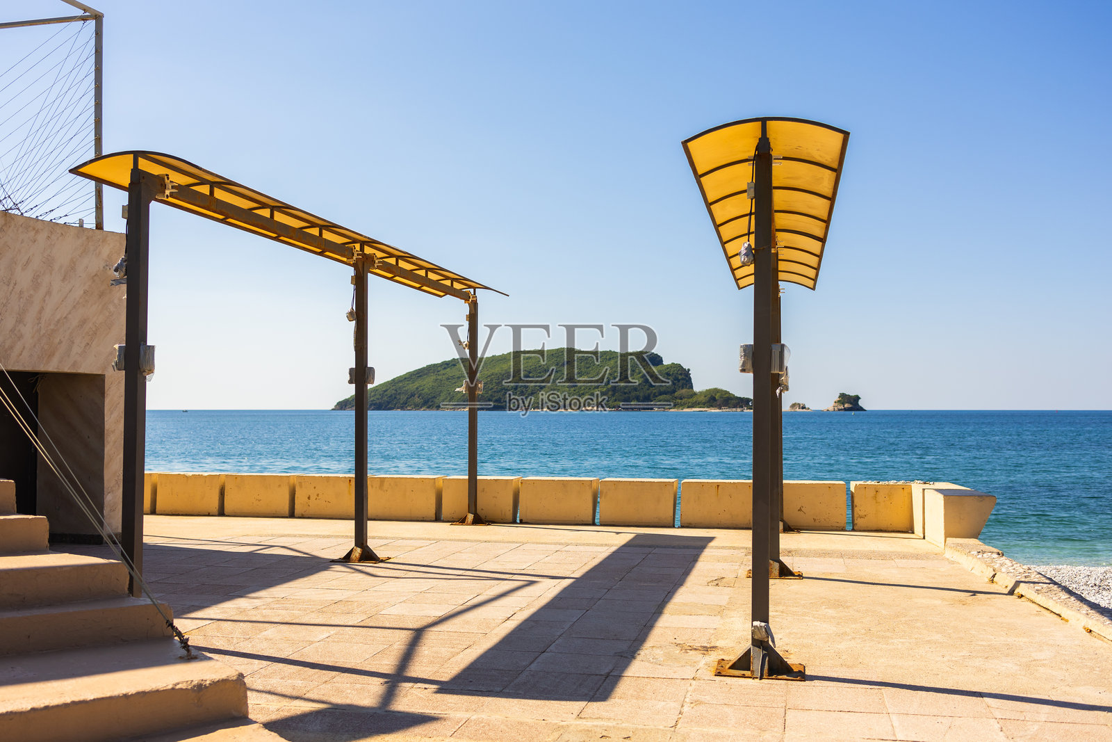 海滨露台，可欣赏岛屿风光。黑山布德瓦的夏日休闲、现代海滩设施和地中海的宁静照片摄影图片