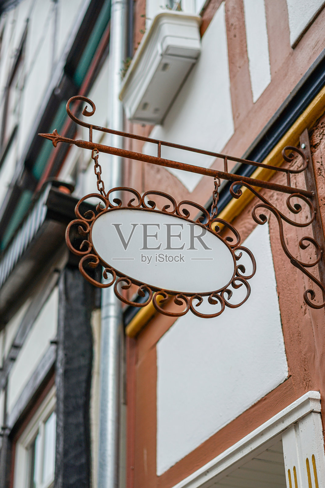 悬挂在建筑物上带有白色椭圆标志的招牌照片摄影图片