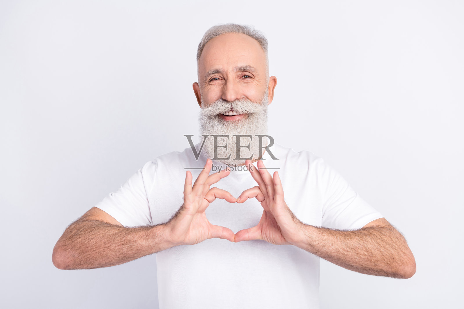 英俊开朗善良深情的男人男友肖像，他比划着心形符号，孤立在浅灰色背景上照片摄影图片