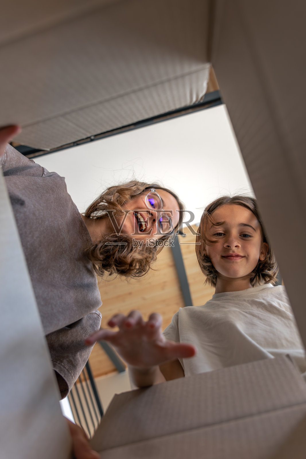 两个女孩在一个盒子上，手在画面中，脸上洋溢着真诚的笑容。从内部拍摄的视角。照片摄影图片