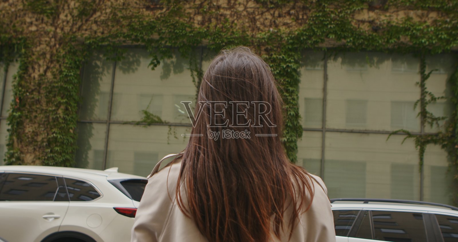 留着长发的女子站在爬满常春藤的墙前照片摄影图片