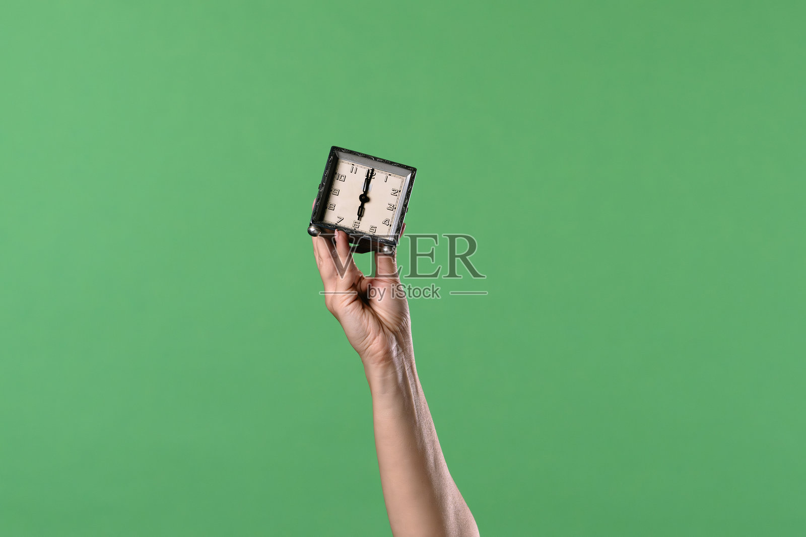 绿底背景上手持复古时钟的女性手部照片摄影图片