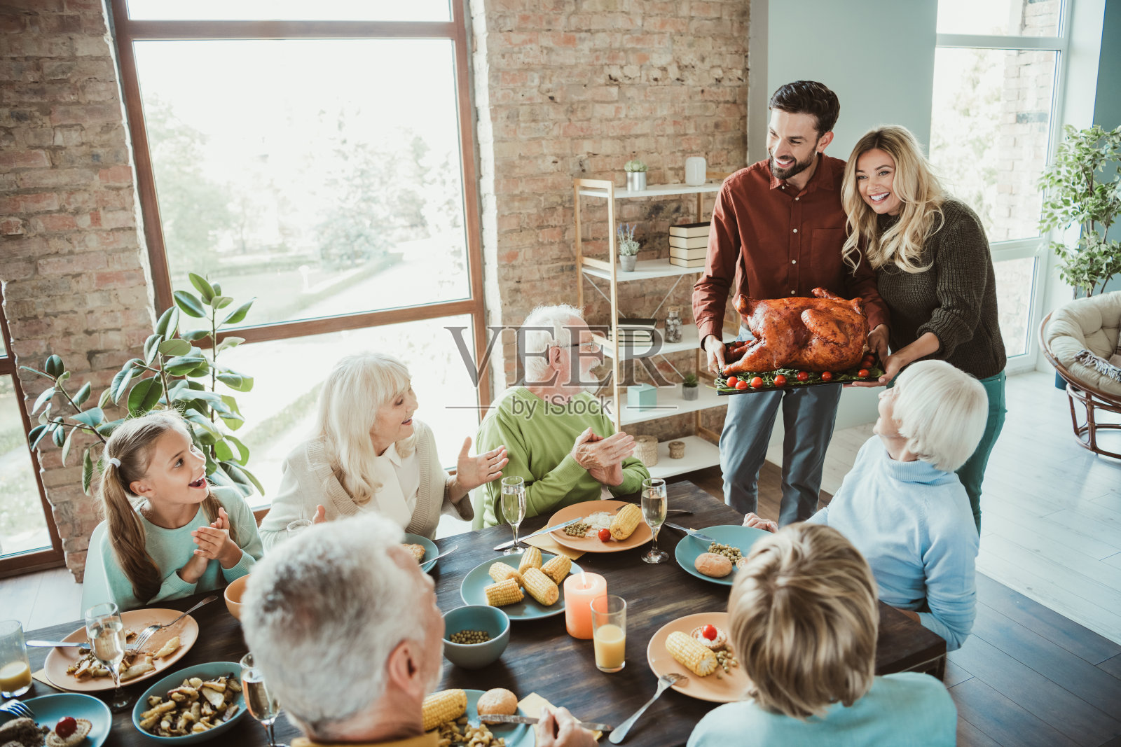 欢乐的感恩节聚会，朋友们在阳光明媚、温馨的家中供应金黄的火鸡，充满爱与欢笑的搞笑家庭盛宴照片摄影图片