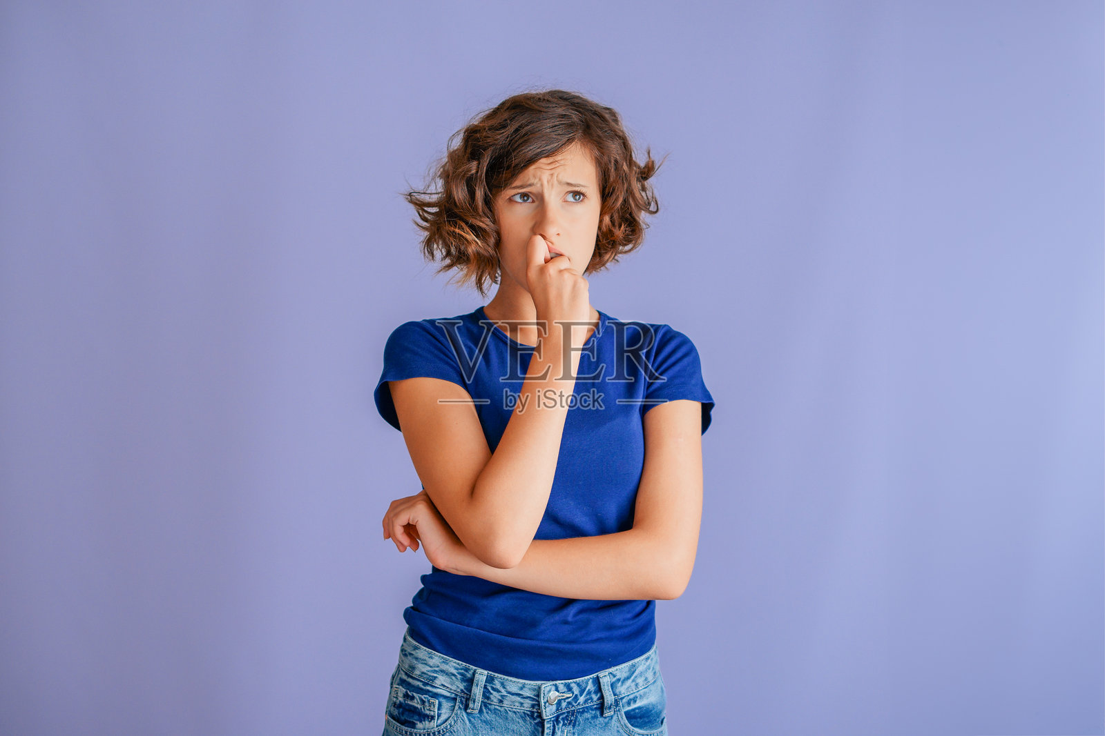 在一个充满活力的蓝色工作室背景下，一位年轻女性在考试前焦虑地表现出担忧的神情，正承受着巨大的压力。照片摄影图片