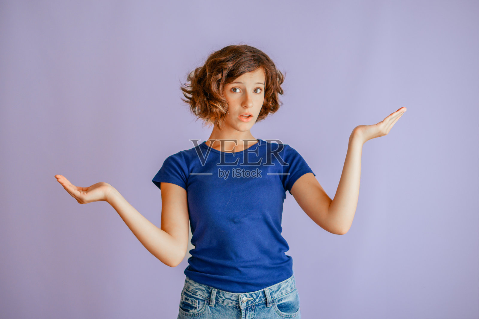 一个专注的年幼孩子，双手权衡着选择，表达着做决定的样子，在充满活力的蓝色工作室背景下，散发出思考和专注的能量，适合用于购物场景。照片摄影图片