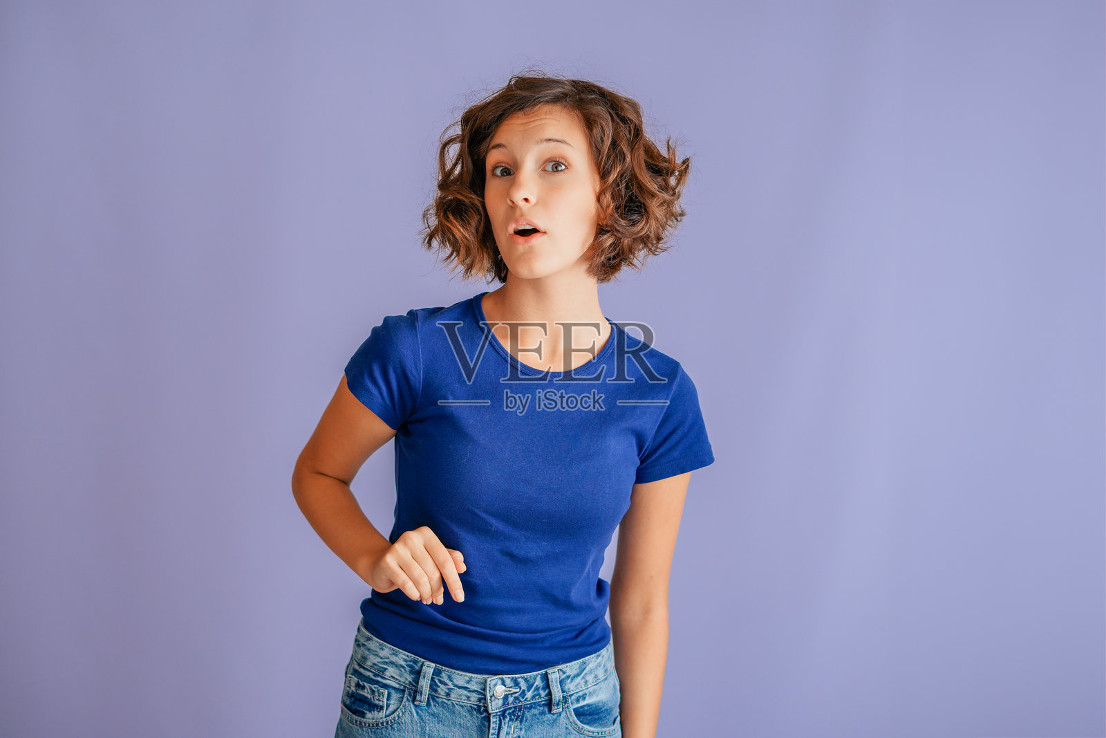 一位专注的女学生，脸上带着好奇和感兴趣的表情，在充满活力的蓝色工作室背景下，展现出探索的专注氛围和投入的能量。照片摄影图片