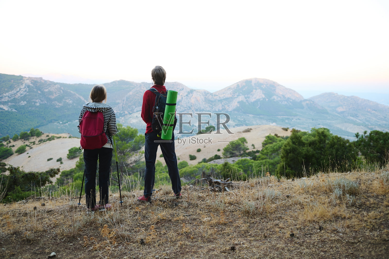 徒步者在黎明时分站在山顶俯瞰山脉照片摄影图片