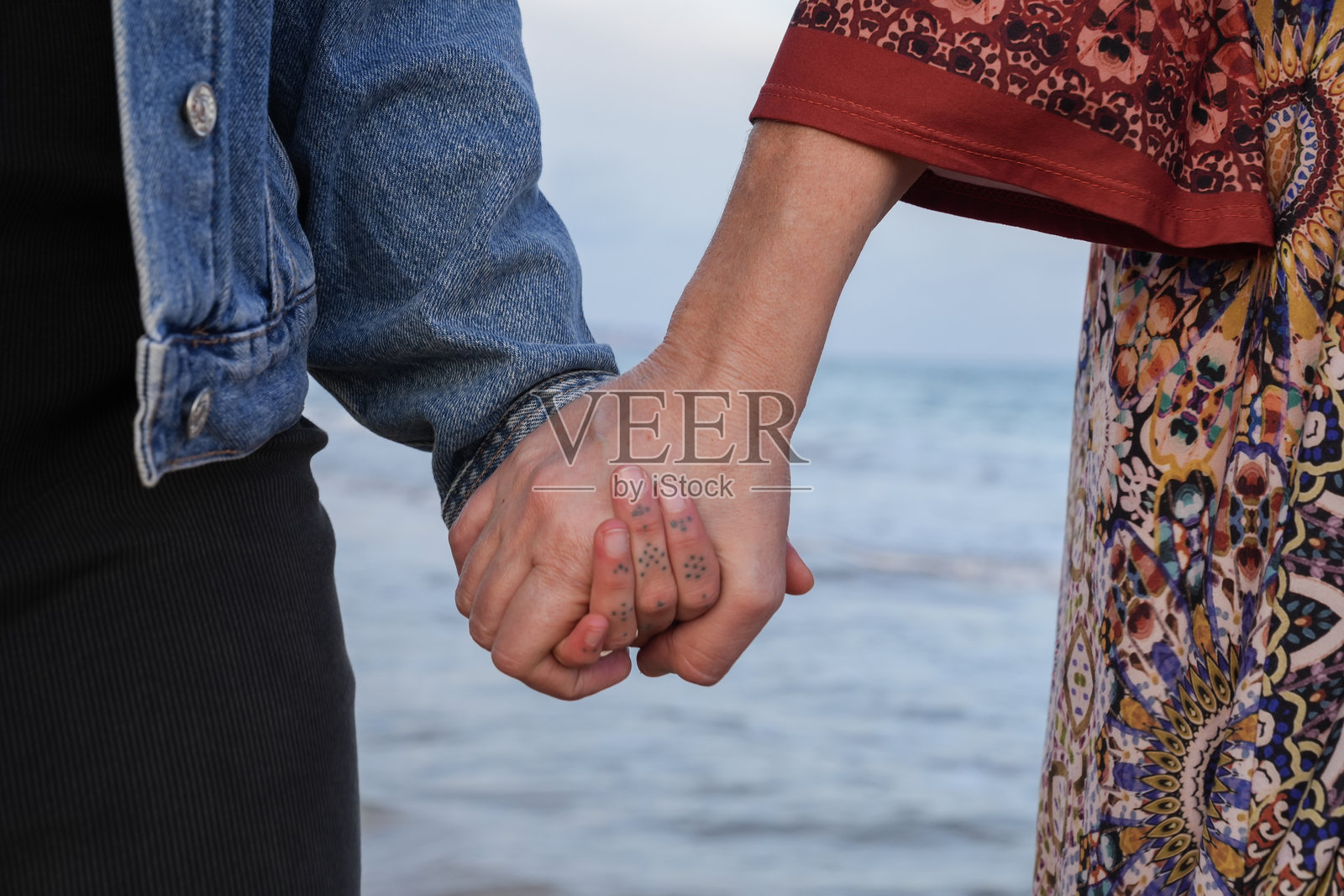 母女俩手牵手在海滩上，展现情感支持照片摄影图片