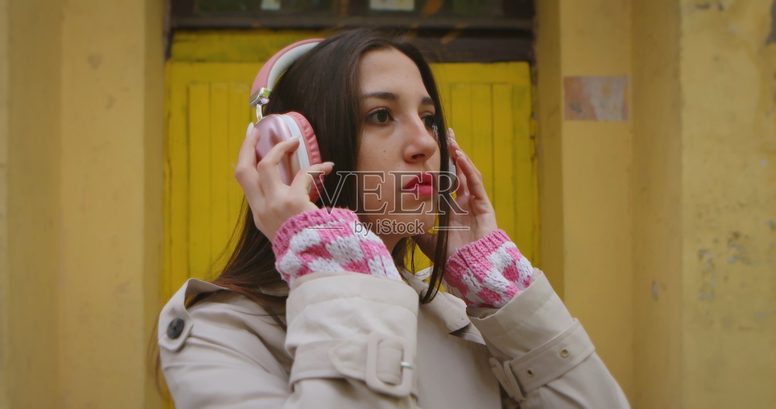 戴着粉色耳机的年轻女子在听音乐照片摄影图片