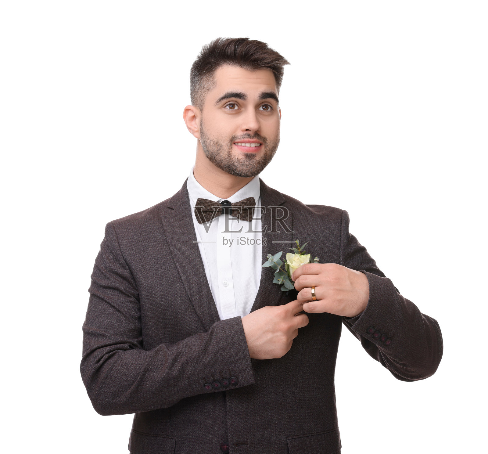 英俊的年轻新郎胸前佩戴着胸花，背景为白色。婚礼配饰照片摄影图片