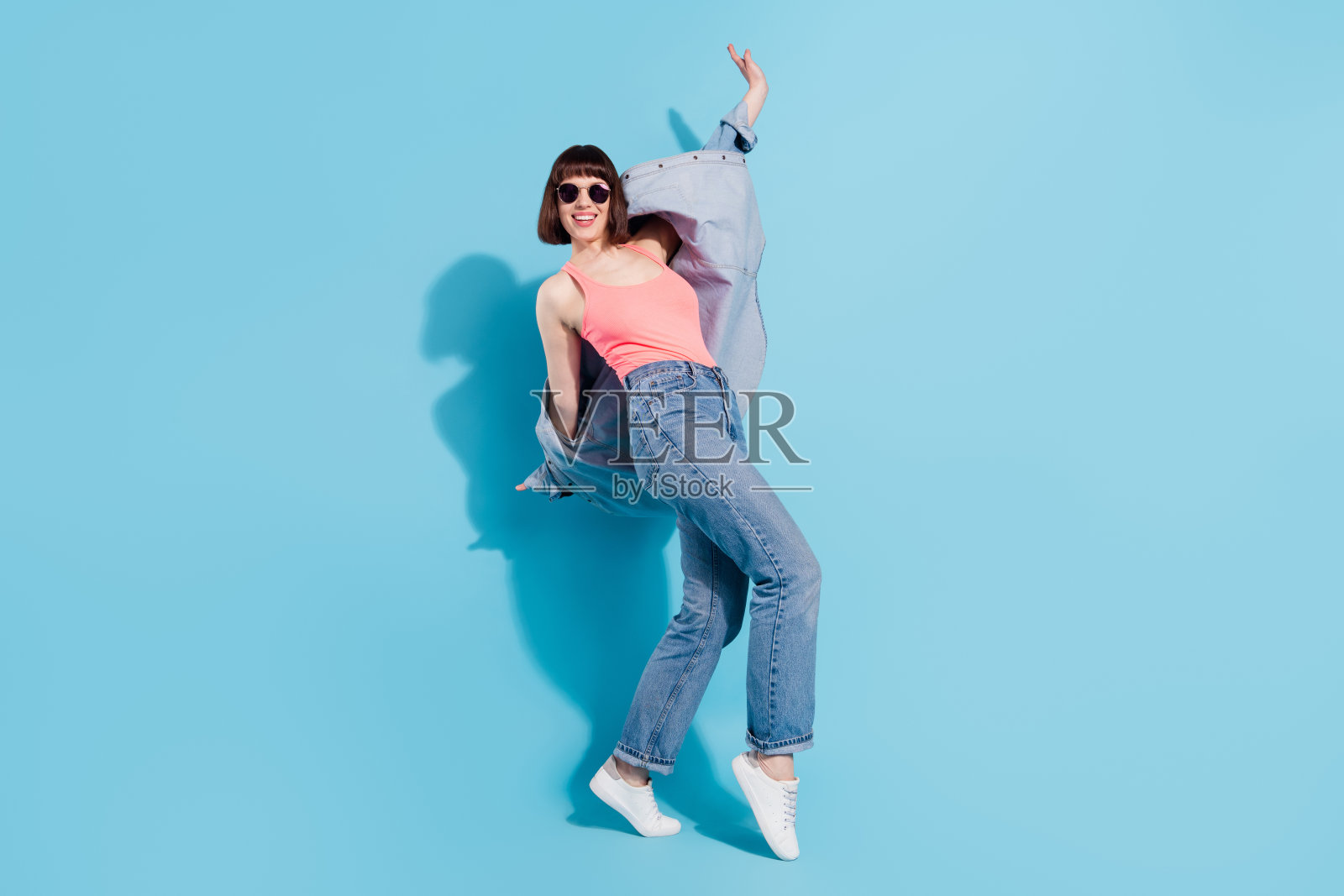魅力十足、活泼开朗、时髦的女孩，尽情享受在俱乐部玩乐的全身照，背景为明亮的蓝色照片摄影图片