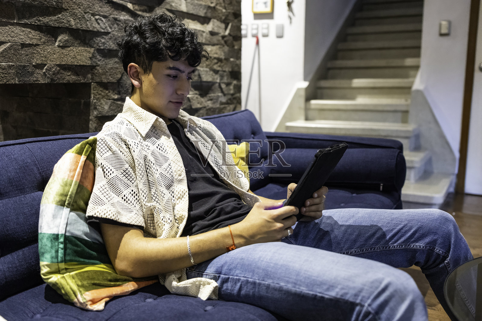 年轻男子在客厅沙发上使用数码平板电脑照片摄影图片