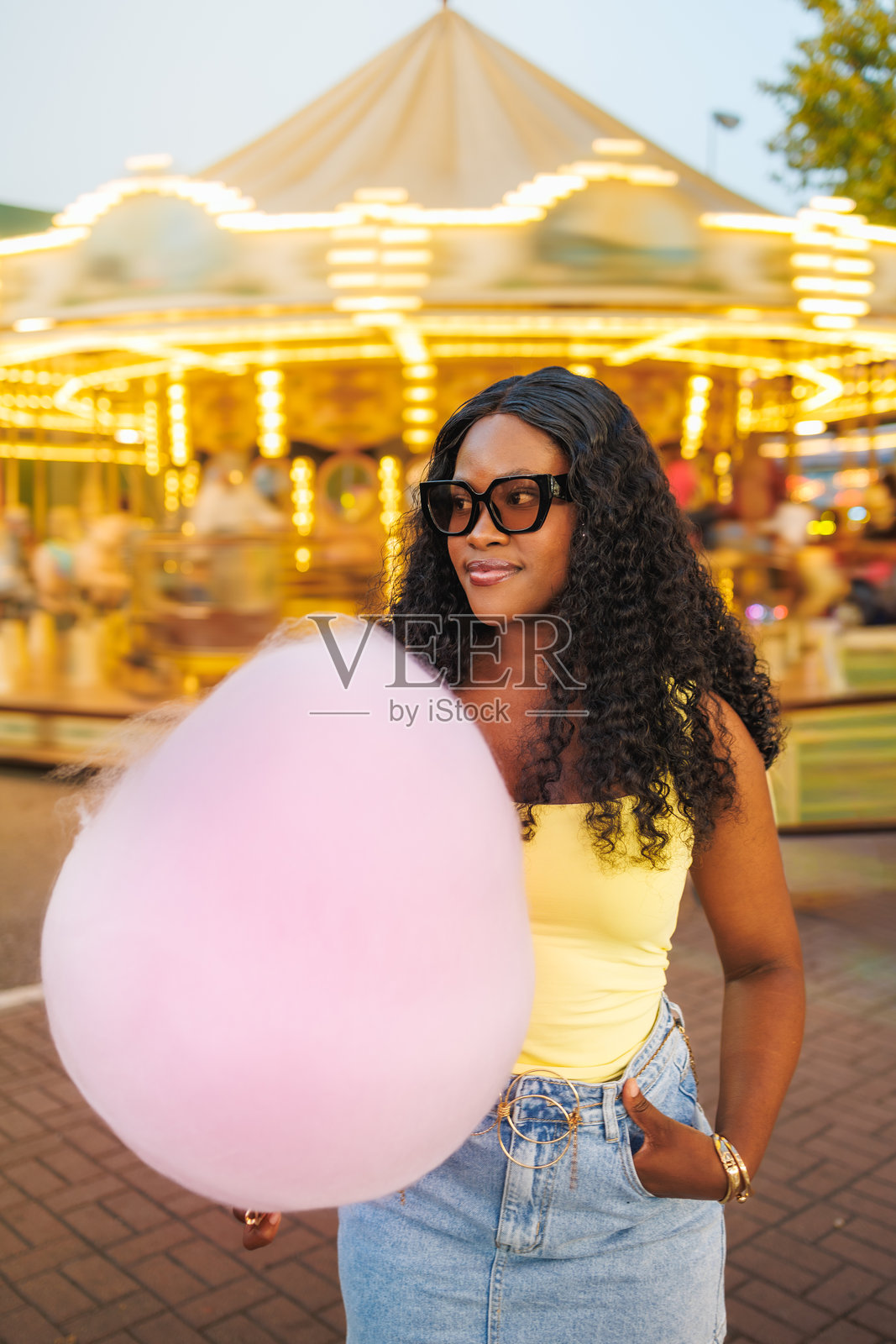 年轻的黑人女性在旋转木马前拿着粉色棉花糖照片摄影图片