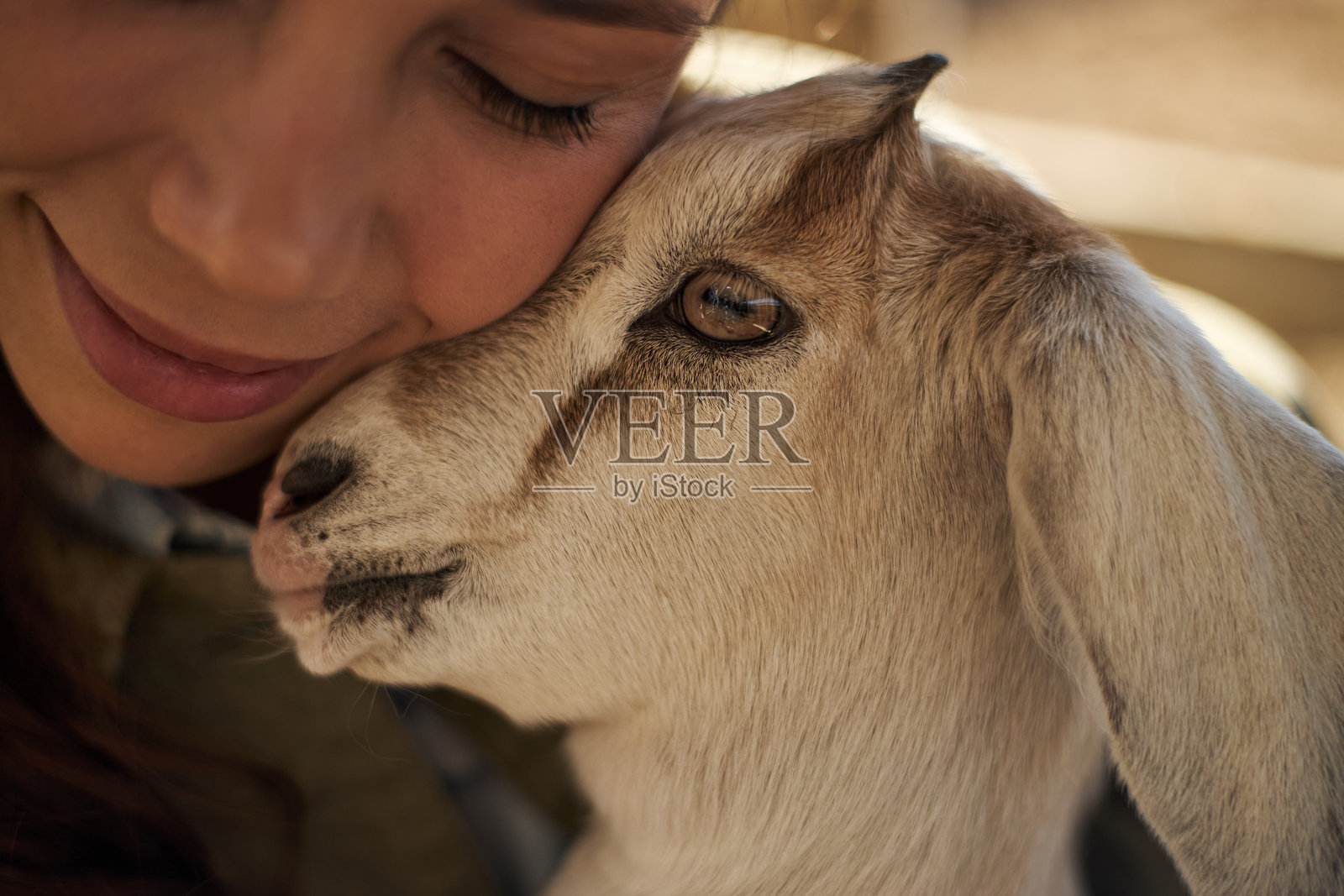 一位年轻的高加索女性在户外抱着小山羊微笑照片摄影图片