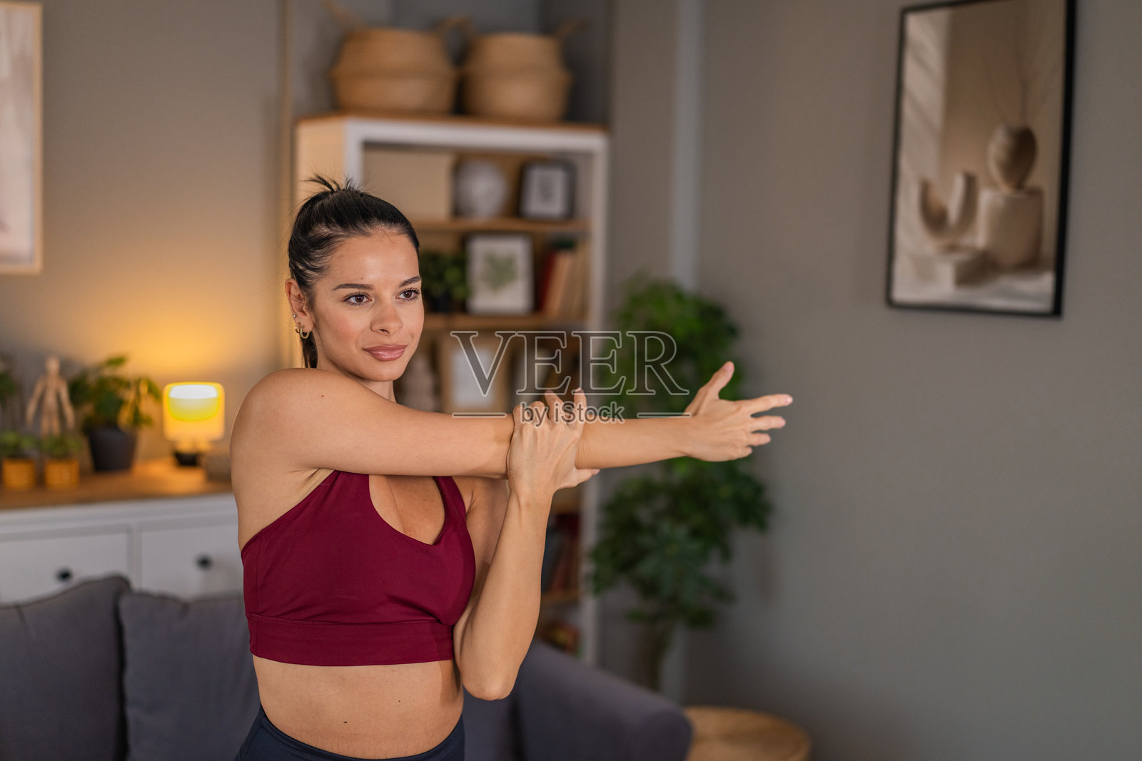 美丽的女性运动员在家进行健身训练并伸展手臂肌肉。照片摄影图片