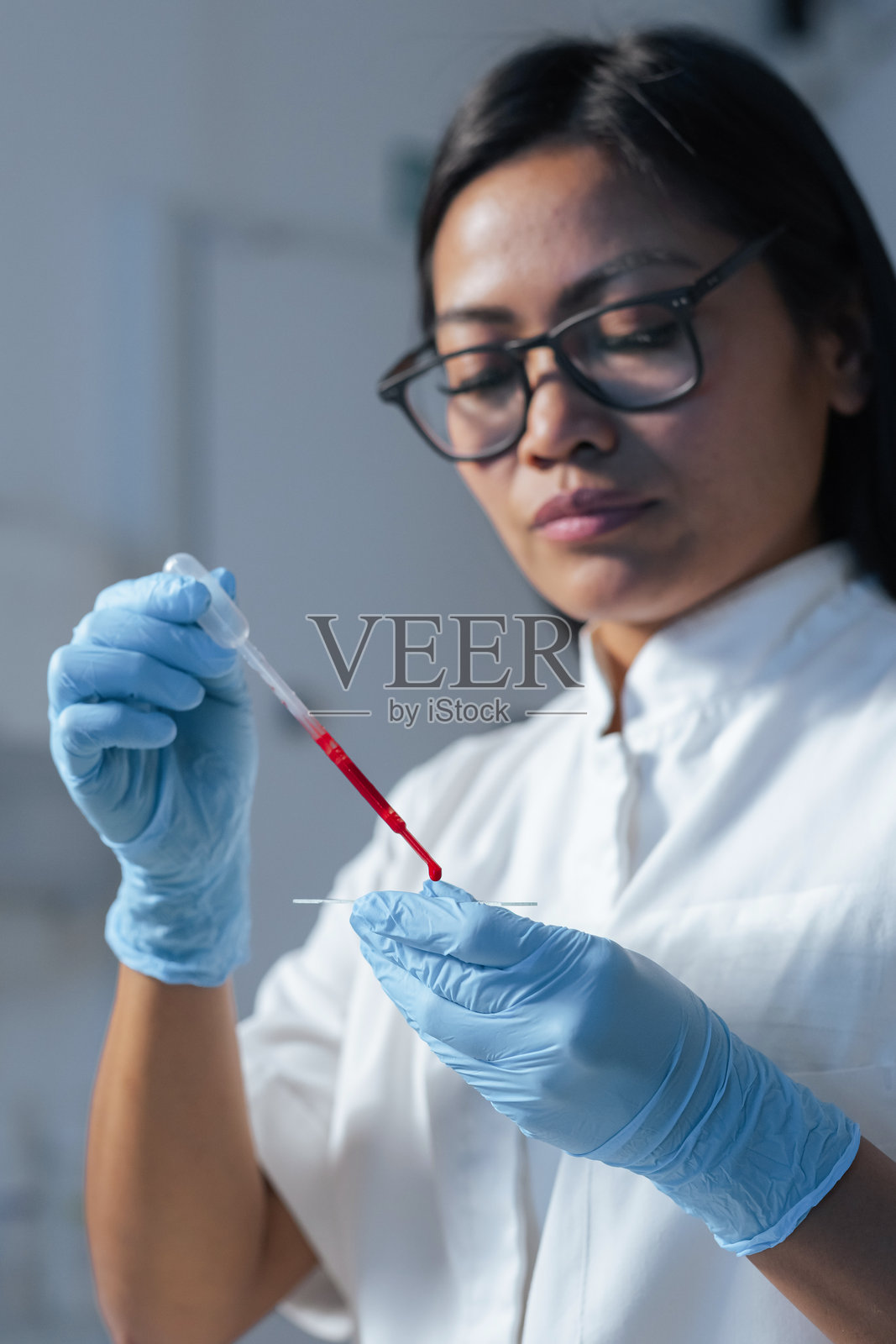 女实验室技术员在显微镜载玻片上移取血液样本照片摄影图片