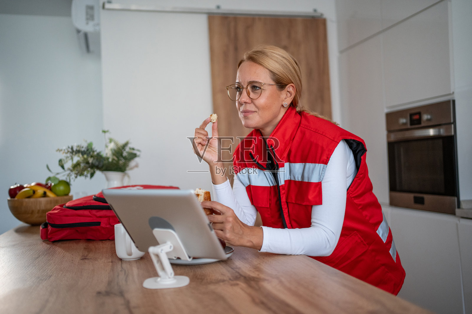 一名女急救人员在休息时边吃东西边看平板电脑照片摄影图片