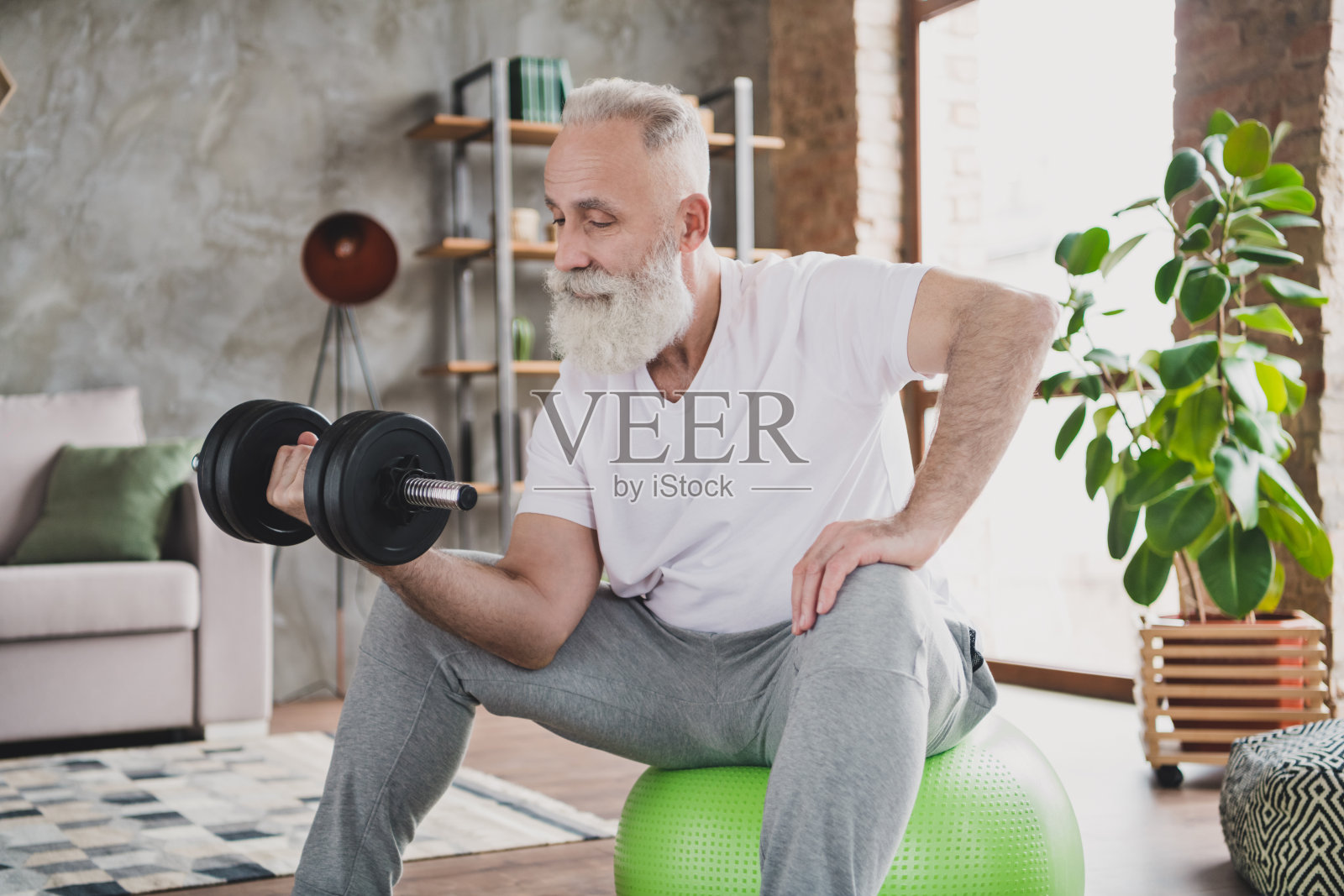 帅气自信成熟的男人在家举哑铃进行力量训练，进行肌肉增长照片摄影图片