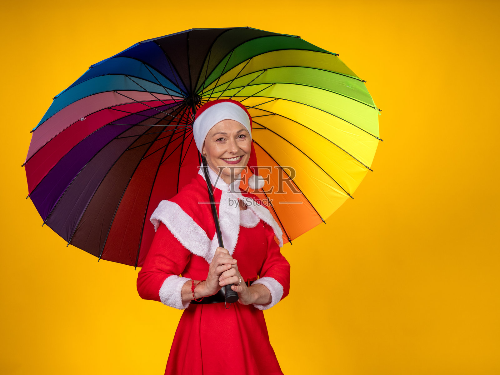 身穿圣诞老人服装的女子手持彩虹雨伞照片摄影图片