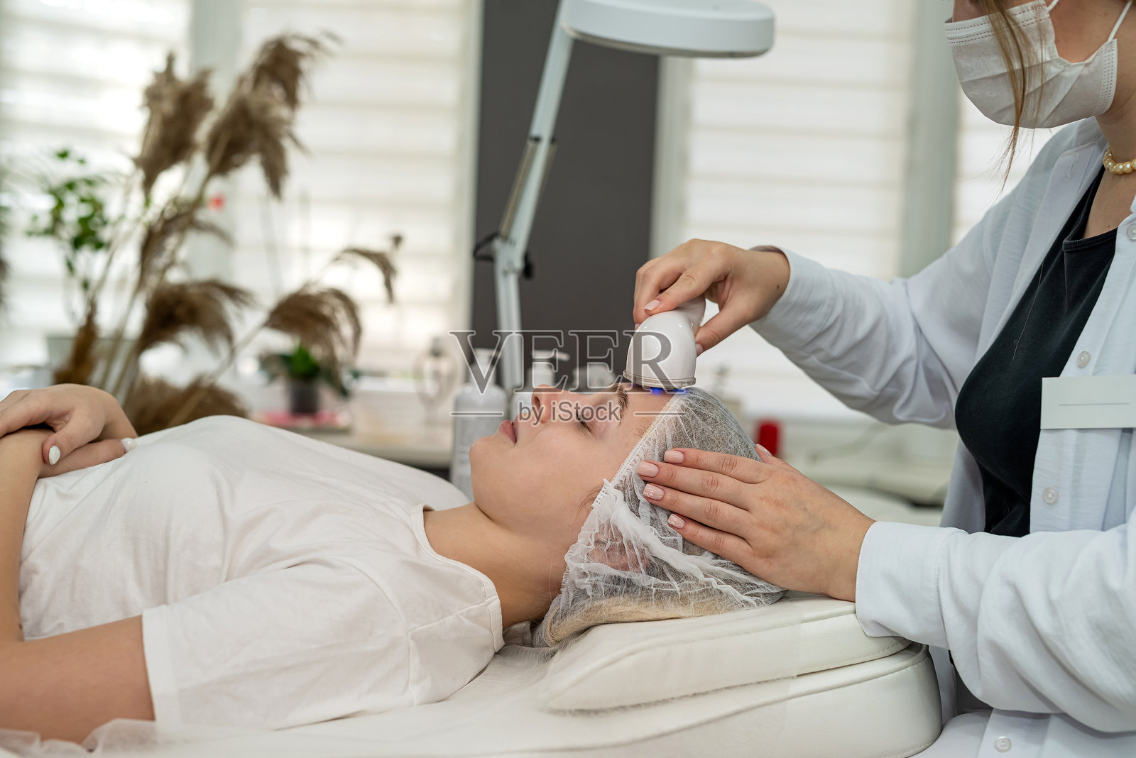 美容师为女性面部进行超声波紧肤美容以达到年轻化效果照片摄影图片